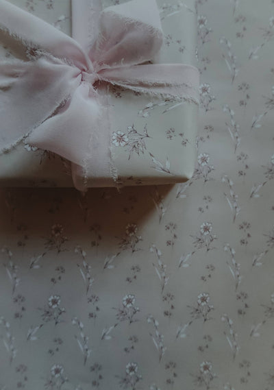 
                    
                      Vintage Blooms wrapping paper, light beige floral pattern, on a wrapped gift box with a pink frayed silk ribbon bow,…
                    
                  