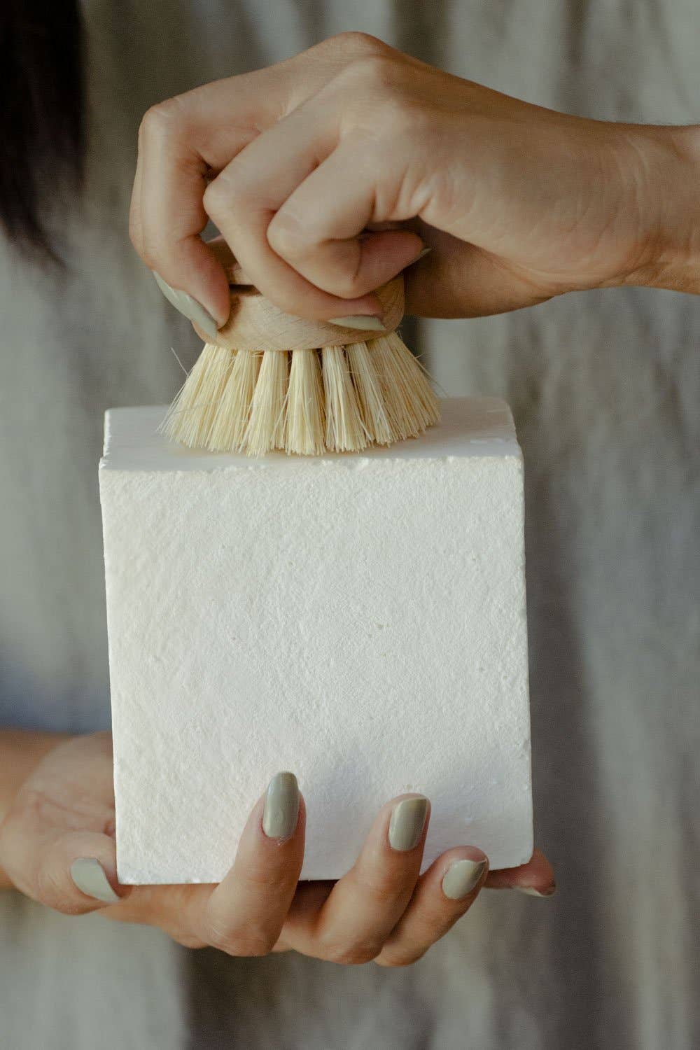 Dish Block Solid Dish Soap, white rectangular block held by a hand, another hand scrubbing its textured surface with a small…