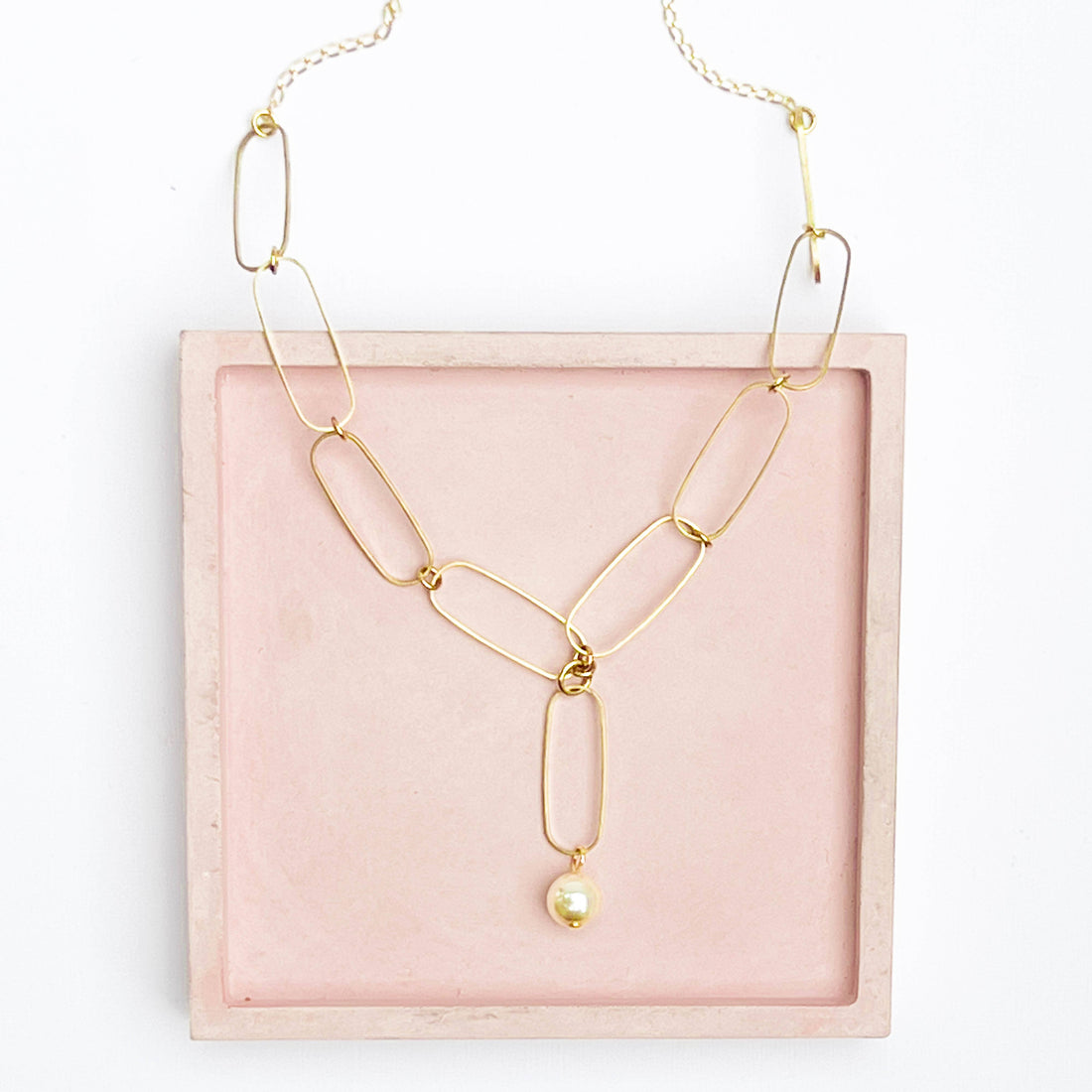 Paperclip Pearl necklace, 24K matte gold-plated chain, Preciosa Crystal pearl. Flat lay in Y-shape on pink tray.