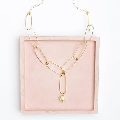 
                    
                      Paperclip Pearl necklace, 24K matte gold-plated chain, Preciosa Crystal pearl. Flat lay in Y-shape on pink tray.
                    
                  