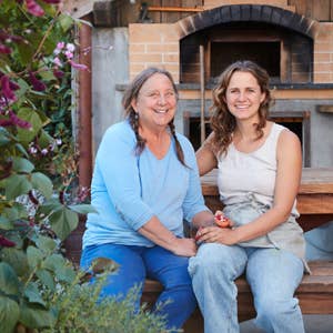 Designing with Dried Flowers book authors, two women smiling outdoors near a rustic brick oven.