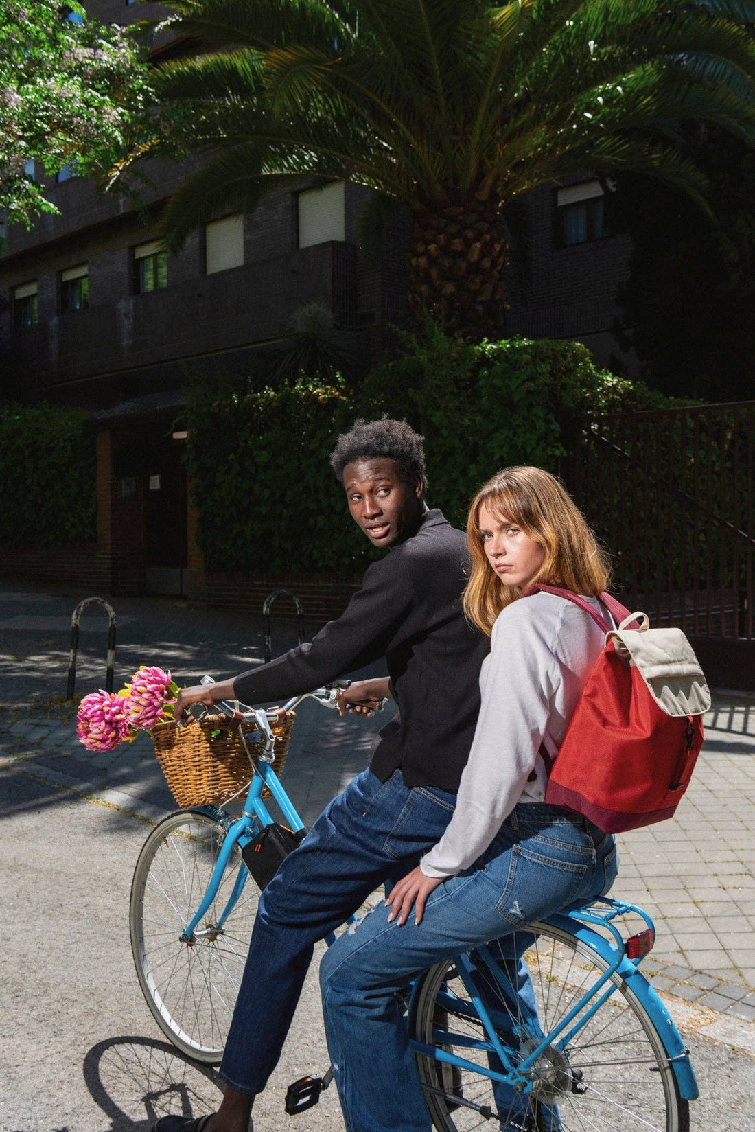 Kaut Cherry Block backpack, red recycled PET fabric with light beige flap, worn on a woman's back while riding a bicycle.