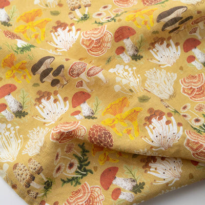 
                    
                      Mushrooms tea towel, close-up of folded mustard yellow linen showing red, brown, white, and yellow mushroom pattern detail.
                    
                  