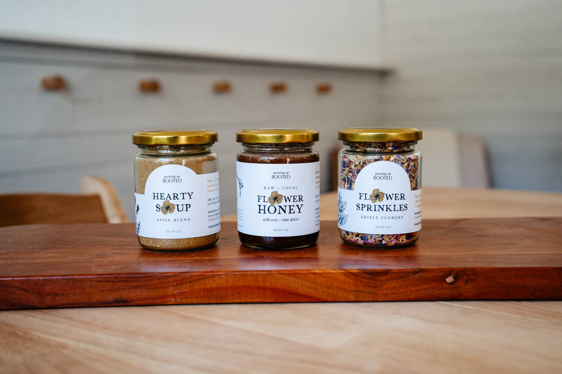 Flower Sprinkles edible decor, colorful organic flower petals in glass jar with gold lid, from an angled view on wood…