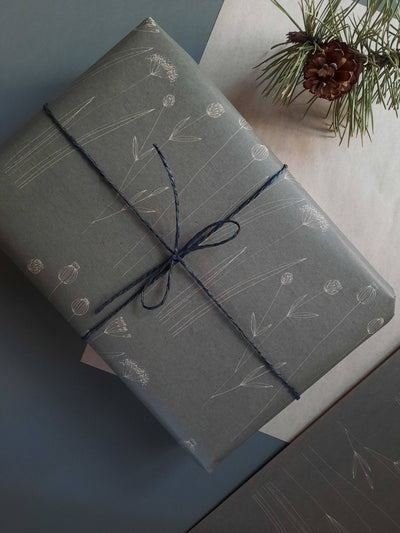 
                    
                      Botanical wrapping paper, dark gray kraft, white illustrated flowers, wrapped gift with dark blue twine and pinecone,…
                    
                  