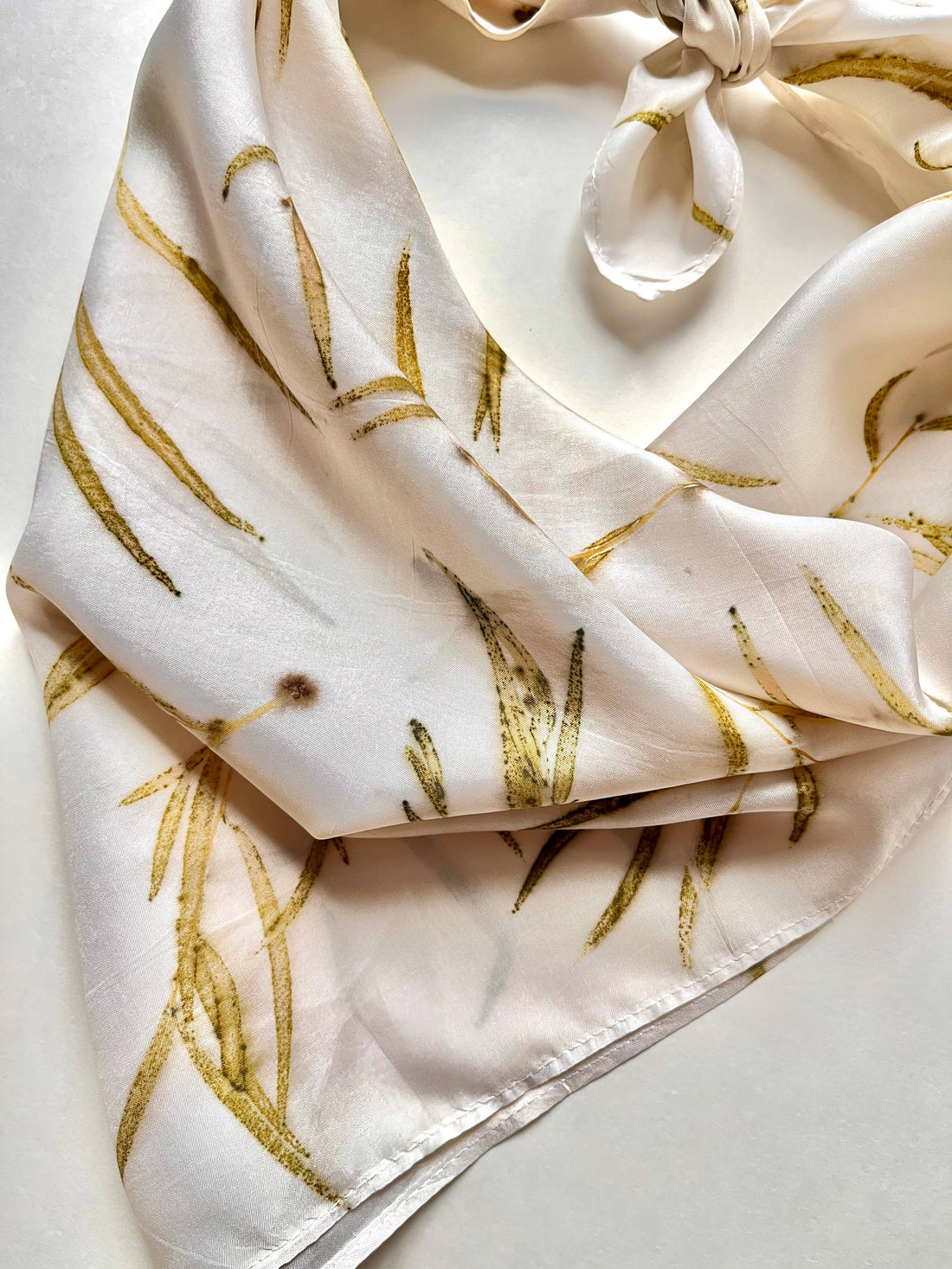 Eucalyptus Grove silk bandana scarf, natural eco-printed feather eucalyptus leaves on cream, folded with a knot detail.