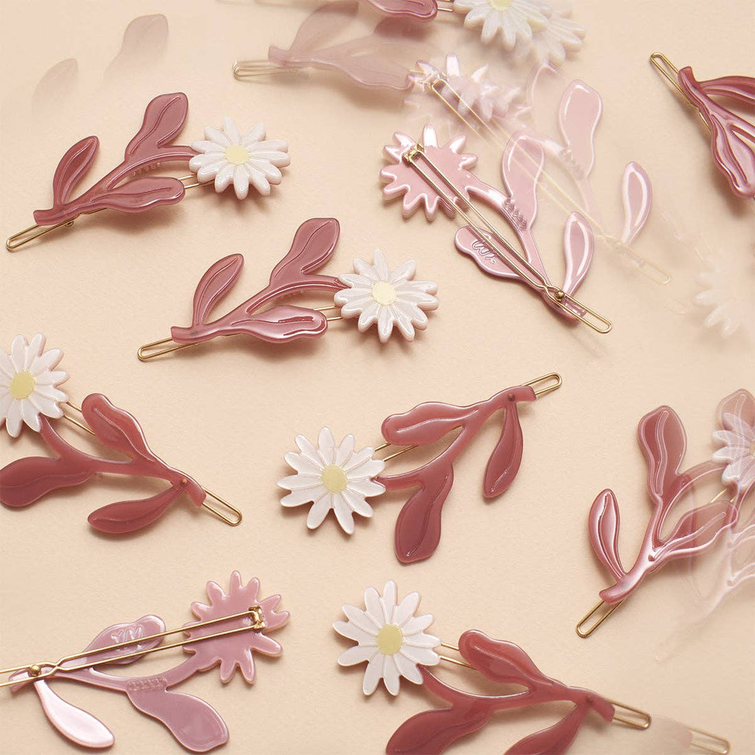 Marguerite Daisy Barrette Set, pink cellulose acetate leaves with white daisy flowers, scattered top-down view showing…
