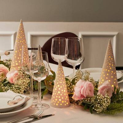 
                    
                      Nobili Ceramic Cone tealight holders, off-white ceramic, glowing dots, grouped on a festive dining table with pink flowers.
                    
                  