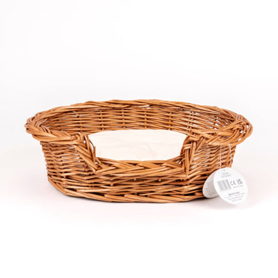 
                    
                      Wicker Dog Basket, natural woven willow with off-white cotton cushion, angled view showing weave detail and product tag.
                    
                  