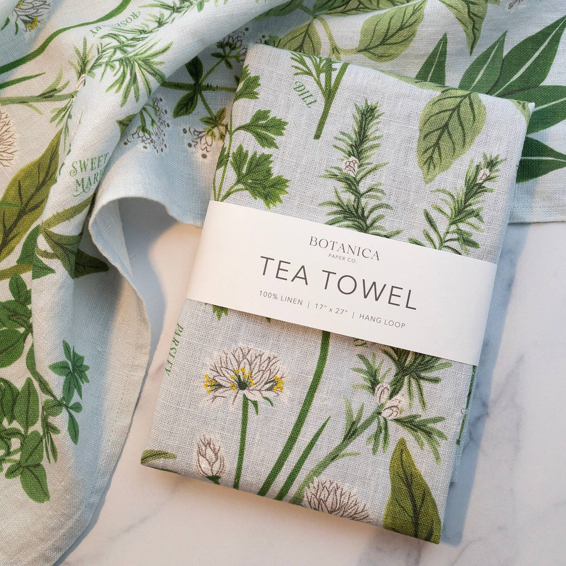 Botanica Paper Co. Herb Garden Linen Tea Towel, light grey organic linen with green botanical pattern, folded packaged…