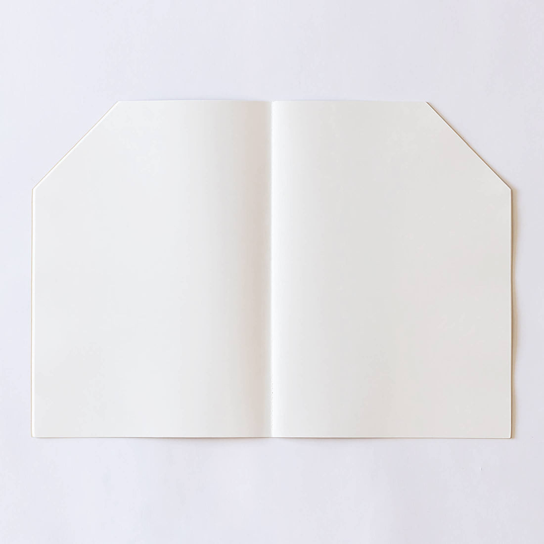 Jumbo House coloring book, open flat showing blank cream paper pages, with its characteristic central fold and angled top…