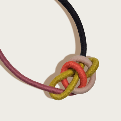 
                    
                      Water Bowline necklace, close-up knot with interwoven black, maroon, olive, coral, and pale pink yarn-wrapped cording.
                    
                  