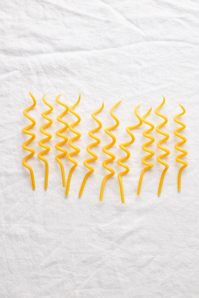 
                    
                      Waxing Moon Twirl Beeswax Birthday Candles, set of eight yellow spiral candles, flat lay on white textured linen.
                    
                  