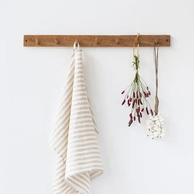 
                    
                      MagicLinen Premium Linen Tea Towel, 100% European flax, natural with light grey stripes, folded on a wooden rack.
                    
                  