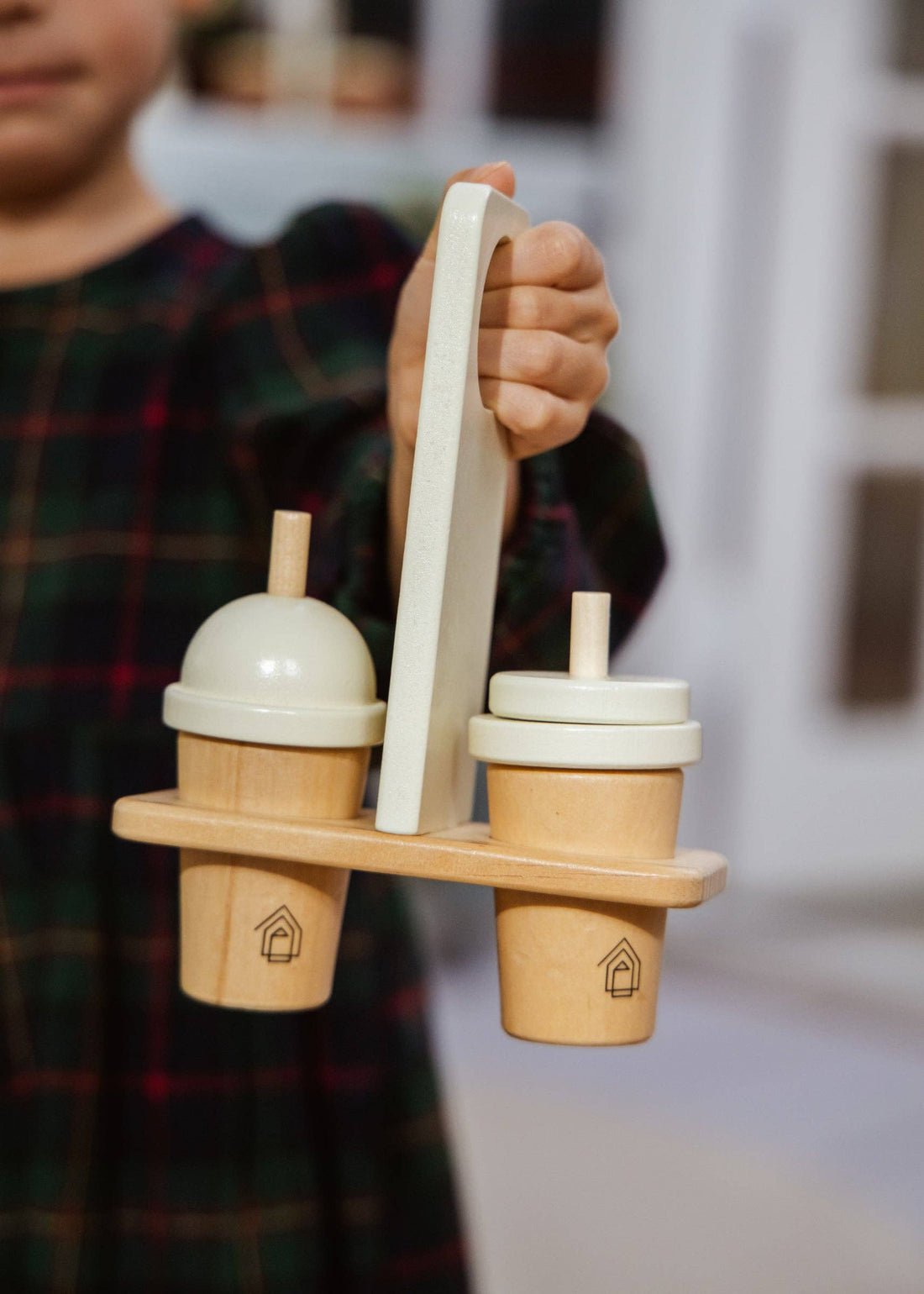 Close-up of Wooden Coffee Maker Set play kitchen toy, natural pine wood & cream cups, held in child's hand.
