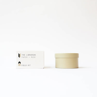 
                    
                      Field Kit The Librarian tin candle, Paper + Musk scent. Light beige tin next to white packaging box, front view on white.
                    
                  