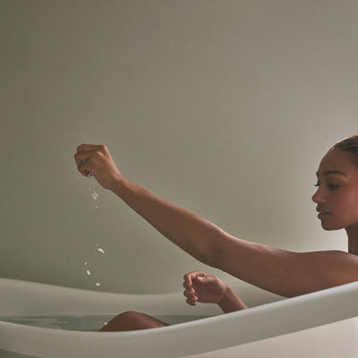 
                    
                      Magnesium Bath Soak, pure magnesium chloride flakes, a hand sprinkling white flakes into bath water.
                    
                  