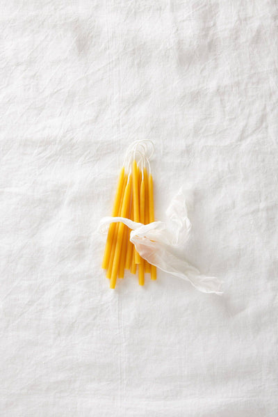 
                    
                      Traditional Beeswax Birthday Candles, pure yellow beeswax, tied in a bundle with a sheer white ribbon, flat lay.
                    
                  