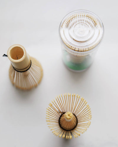 
                    
                      Chasen bamboo tea whisks, natural bamboo. Overhead view: one whisk splayed, one upright handle, with clear container.
                    
                  