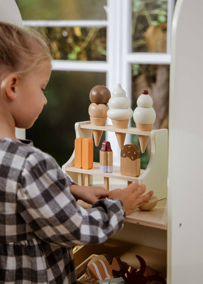 
                    
                      Wooden Ice Cream Stand, play food set, child's hands reaching for natural wood, white, brown, orange treats.
                    
                  