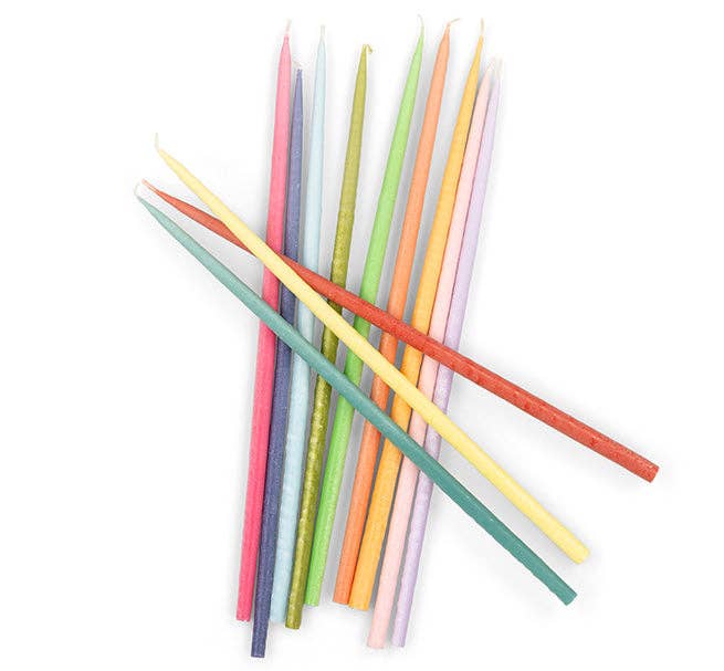 Rainbow Taper Candles, 12 assorted Stearin wax candles, colorful overlapping flat lay arrangement.
