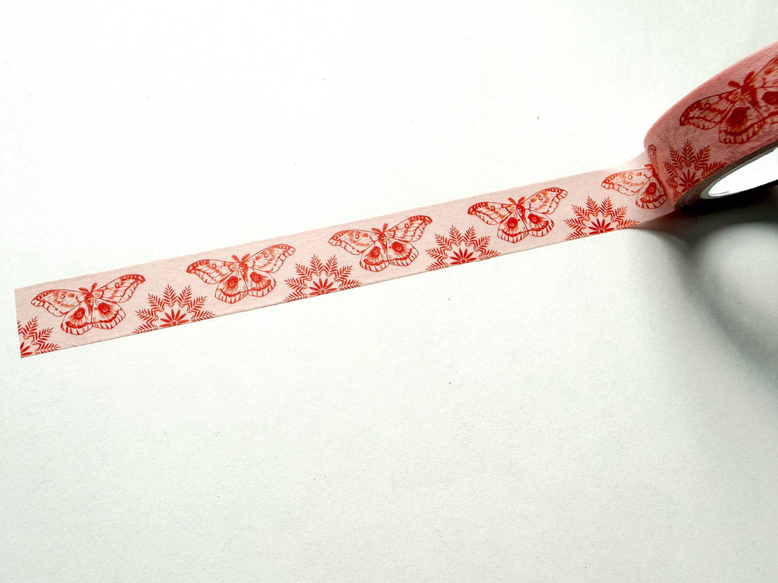 Moths On Pink washi tape, unrolling spool, red moth and fern pattern on light pink rice paper, diagonal view.