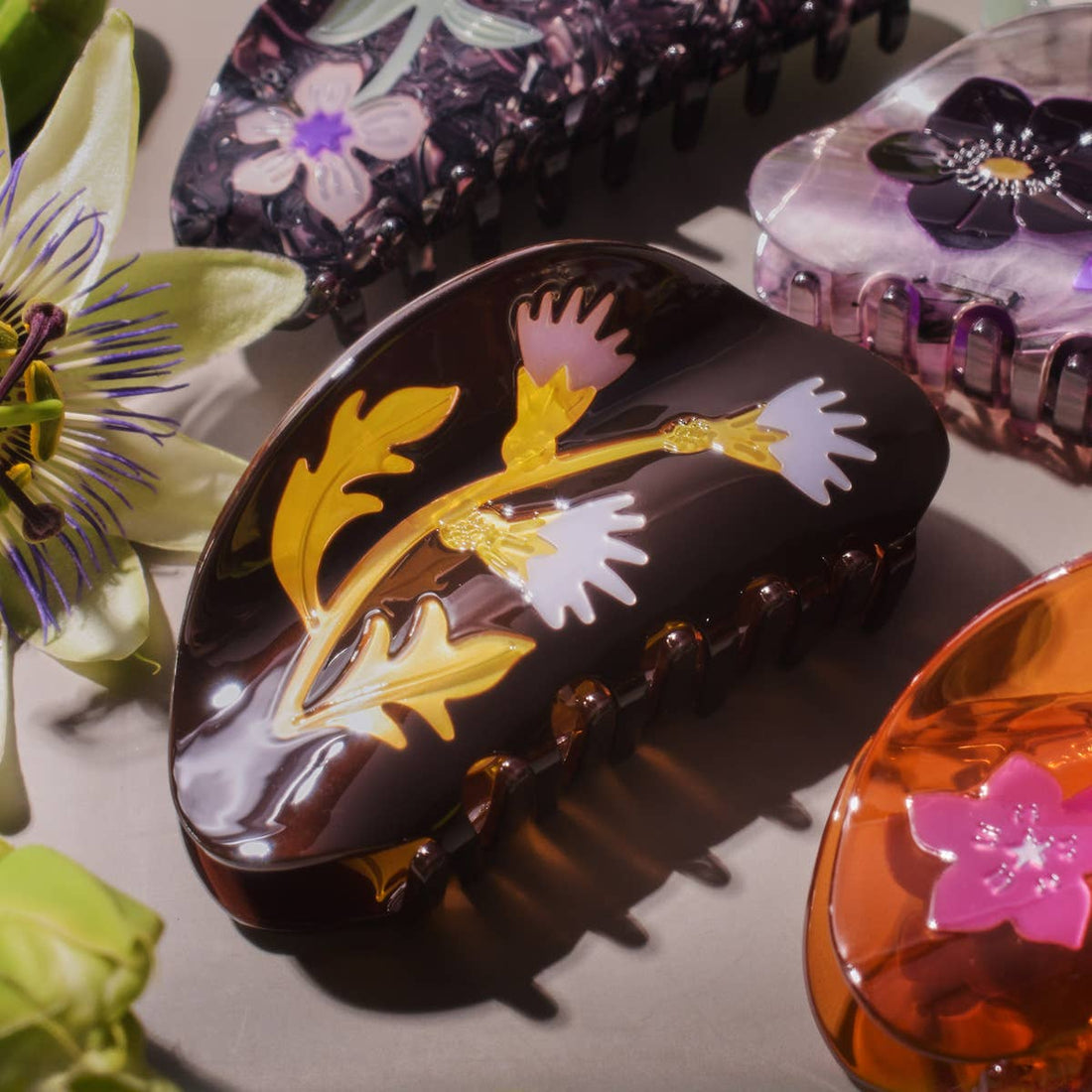 Milk Thistle Hair Claw, dark brown cellulose acetate with yellow leaves and pink and white thistle flower design, close-up…