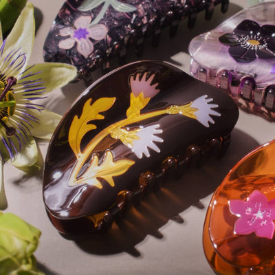 
                    
                      Milk Thistle Hair Claw, dark brown cellulose acetate with yellow leaves and pink and white thistle flower design, close-up…
                    
                  