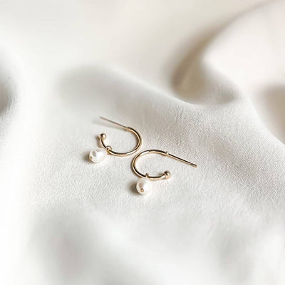 
                    
                      Chloe Pearl hoop earrings, gold-plated with white pearls, flat lay pair showing posts.
                    
                  