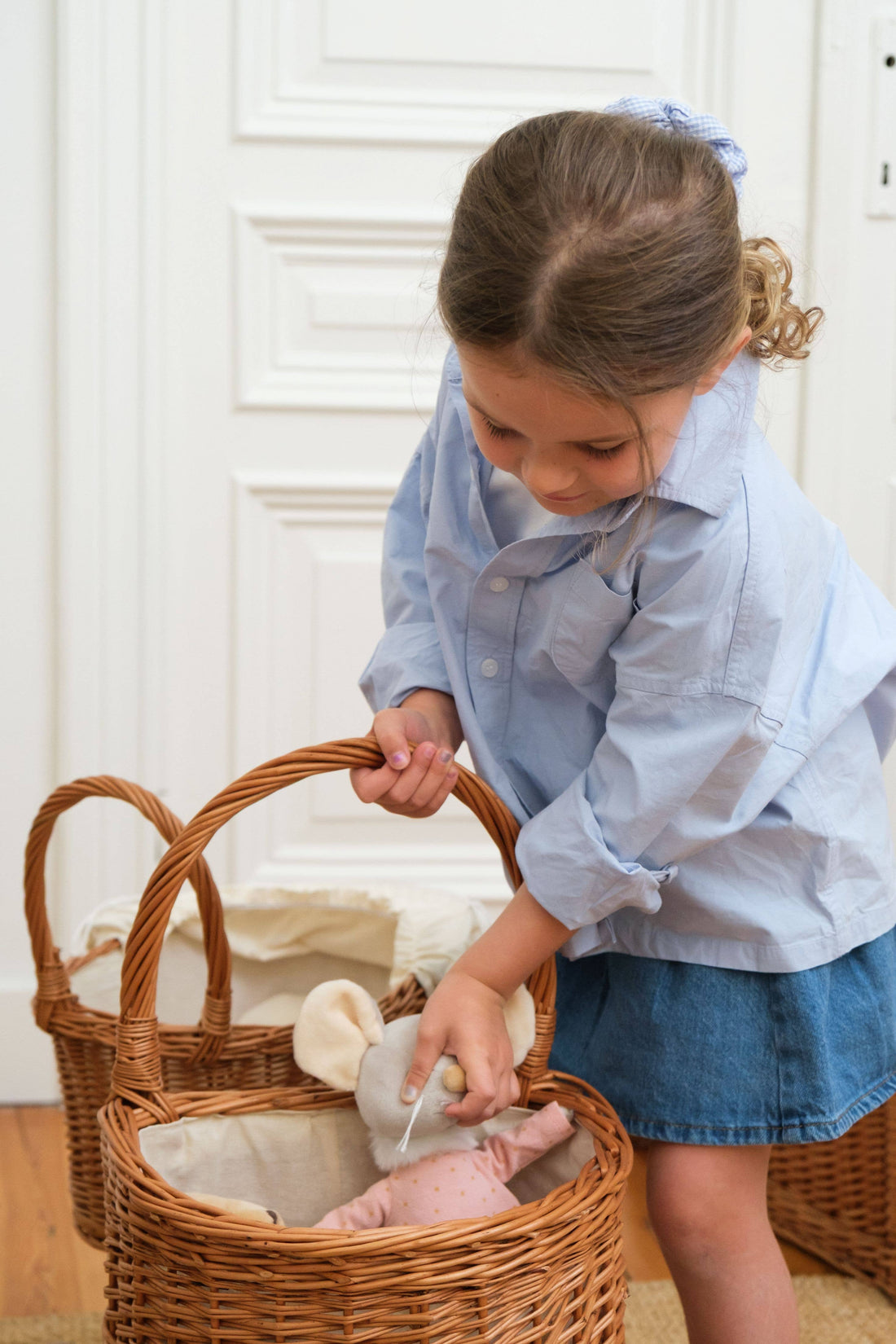 Wicker Shopping Caddy, natural woven wicker with cotton liner, child placing toy inside, demonstrating capacity and size.