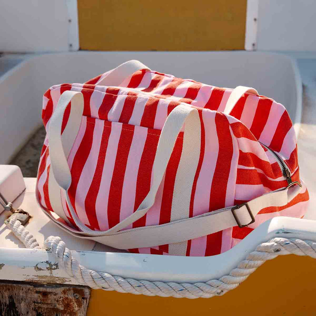 Raphael Weekend diaper bag in tomato and candy pink vertical stripes, textured cotton fabric, angled view showing the top…