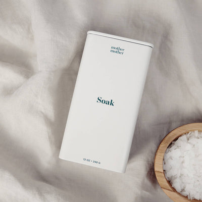 
                    
                      Mother Mother Magnesium Bath Soak white tin, angled view with pure magnesium chloride flakes in a small wooden bowl.
                    
                  