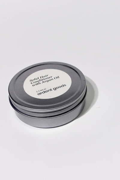 
                    
                      Solid Hair Conditioner with Argan Oil in a round silver tin with white label, angled view showing top and side.
                    
                  