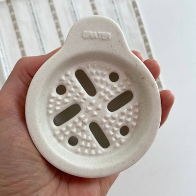 
                    
                      Japanese Ceramic Vegetable Grater piece, off-white speckled porcelain held in hand, showing embossed 'GRATER' and grating…
                    
                  
