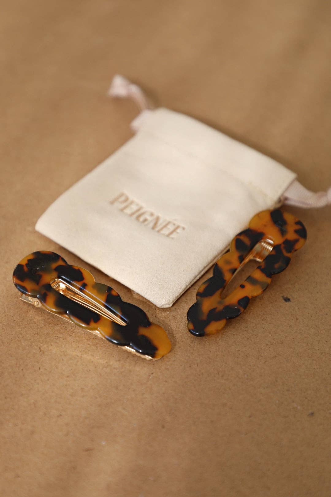 Tortoise cellulose acetate Signature Hair Clips, back view of gold-toned clip mechanism, with branded Peignee pouch.