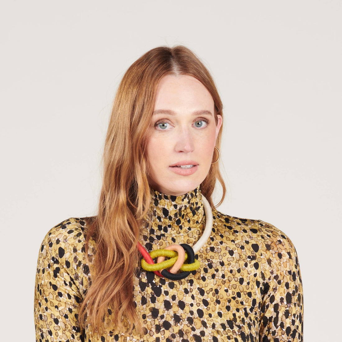 Water Bowline necklace (Spring) with cream, green, black, peach, red yarn cording, worn on model's neck, front view.