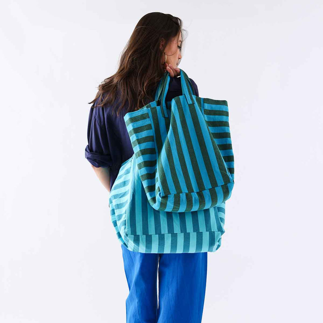 Elisabeth Tote Bag, turquoise & olive stripe cotton, carried over shoulder by person from behind, showcasing bag's large…