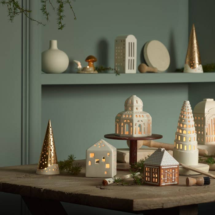 Urbania Town House ceramic candle holder, gingerbread brown and white, illuminated, displayed among other Urbania models.