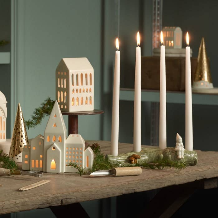 Urbania Church ceramic candle holder, cream Dolomite, glowing warmly from within, presented in a festive tabletop winter…