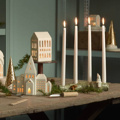 
                    
                      Urbania Church ceramic candle holder, cream Dolomite, glowing warmly from within, presented in a festive tabletop winter…
                    
                  