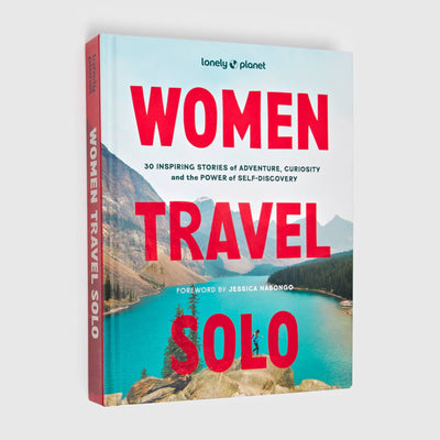 
                    
                      Women Travel Solo hardcover book, angled view showing the red spine and blue lake with mountains cover.
                    
                  