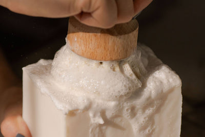 
                    
                      Dish Block Solid Dish Soap, white, actively lathering with a natural wooden dish brush, close-up of thick foam.
                    
                  