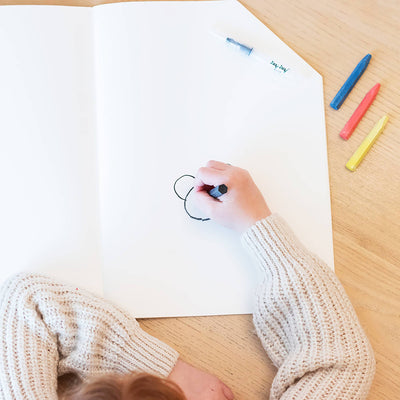 
                    
                      Jaq Jaq Bird Jumbo House coloring book, top-down view of child's hand drawing on open white page; blue, red, yellow crayons…
                    
                  