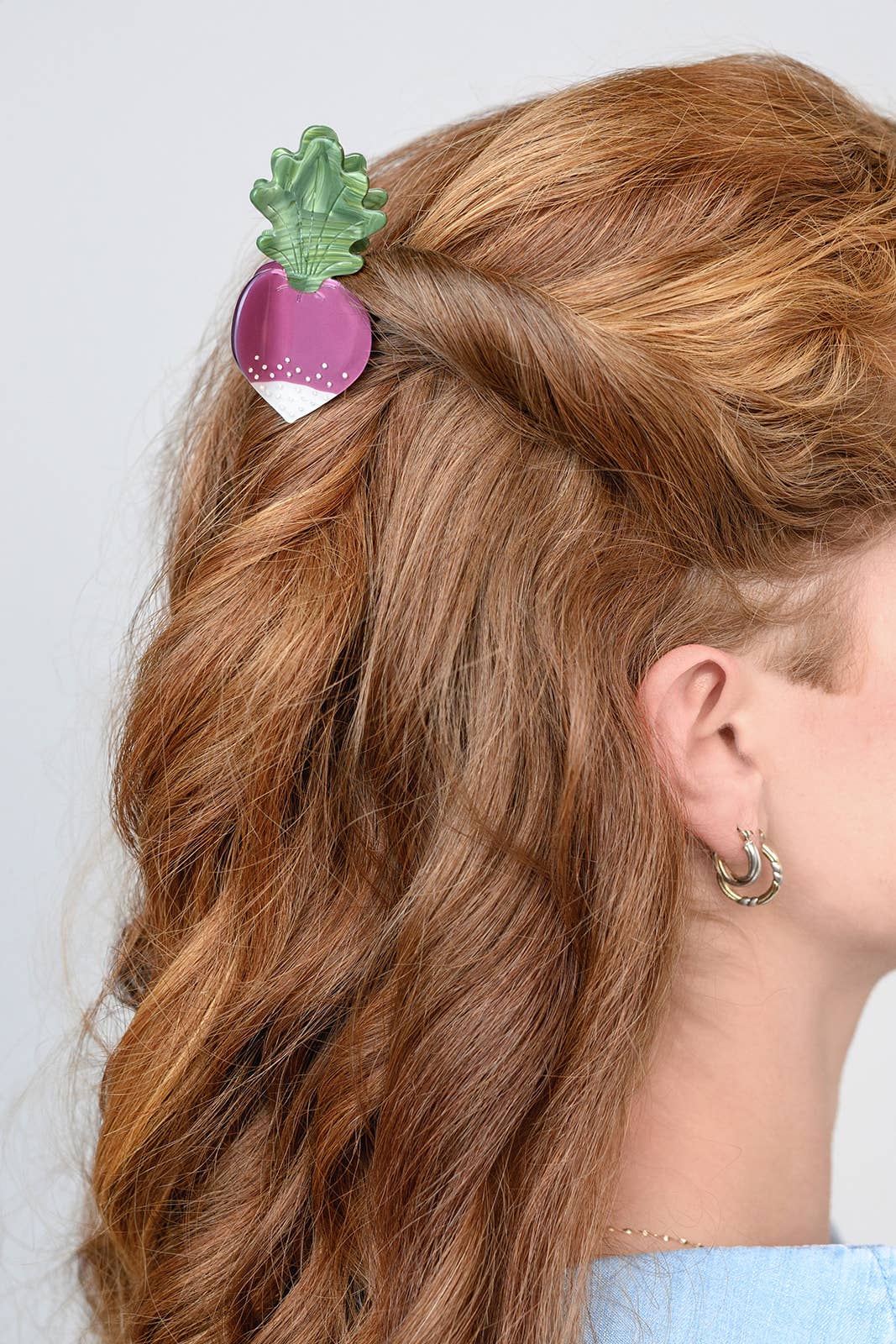 French Radish hair clip, purple and green acetate with white dots, worn securing a twisted half-updo, side view.