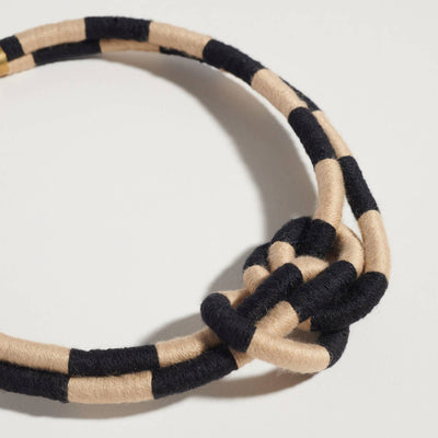 
                    
                      Checkered Double Dragon necklace, black and beige woven textile, close-up of central knot and checkerboard pattern.
                    
                  
