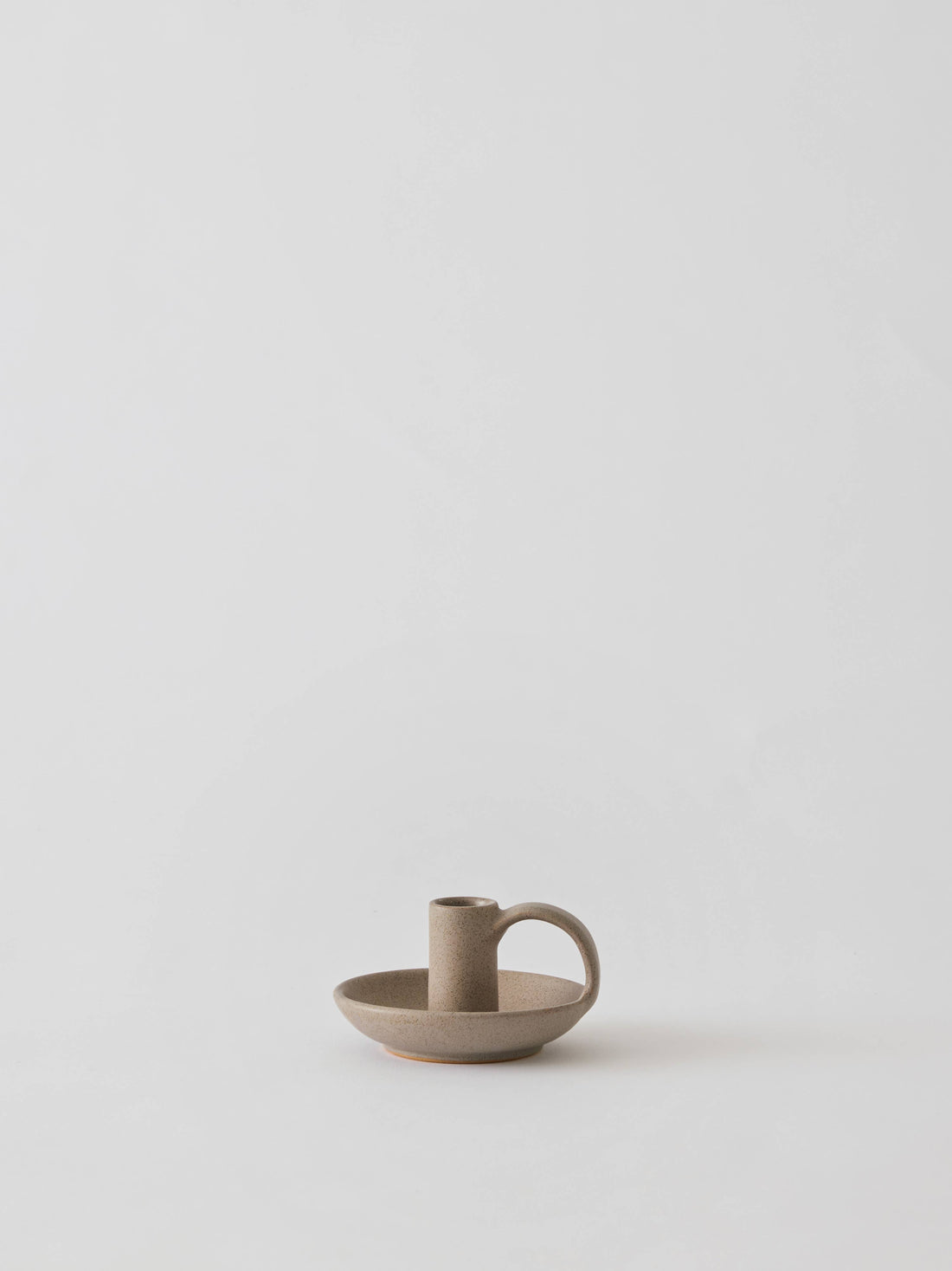 Tell Me More Nimo candle holder, matte sand glazed stoneware with side handle, front view on white.