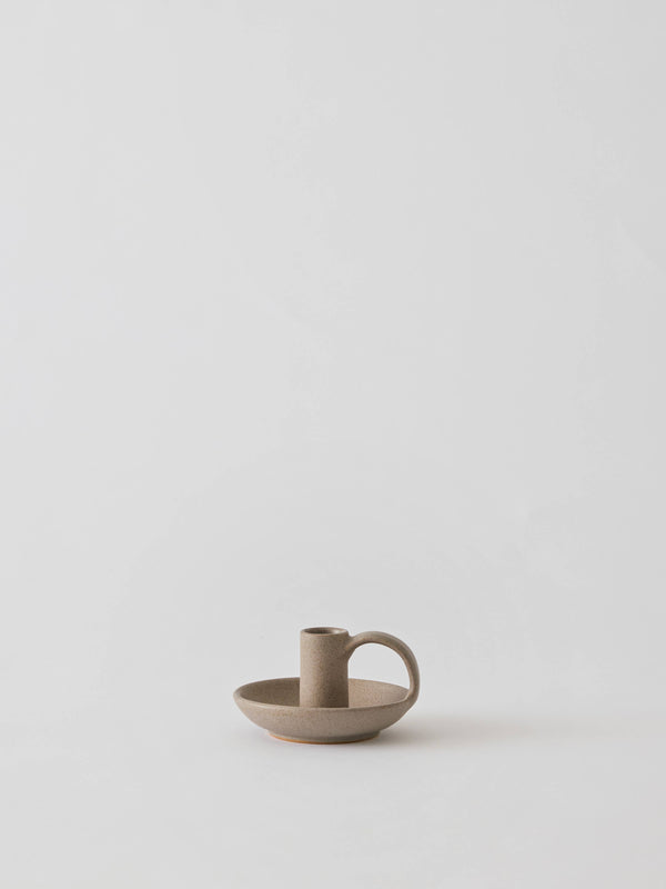 Tell Me More Nimo candle holder, matte sand glazed stoneware with side handle, front view on white.