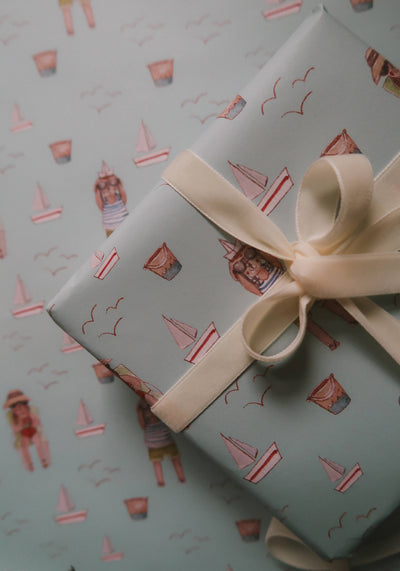 
                    
                      Summer Wrapping Paper, light blue, illustrated by Agnese Grīnberga with sailboats, beach figures & gulls; close-up of gift…
                    
                  