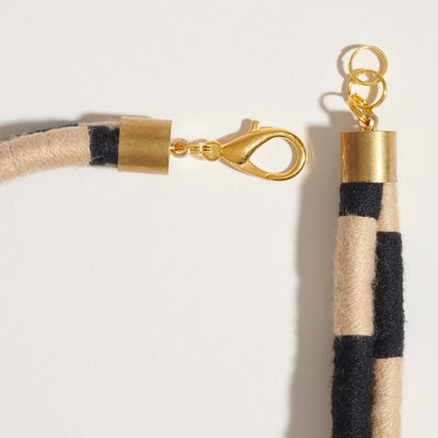 
                    
                      Checkered Double Dragon necklace, black and tan woven cord, brass lobster clasp and extender chain detail.
                    
                  