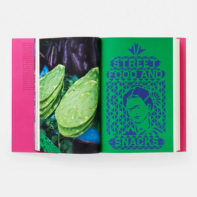 
                    
                      Mexico: The Cookbook open to bright green page with blue Frida Kahlo illustration and photo of dewy green nopal cactus pads.
                    
                  